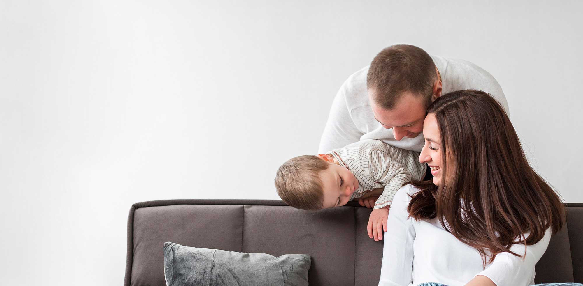 Man, woman, and child sitting on couch in insured home.